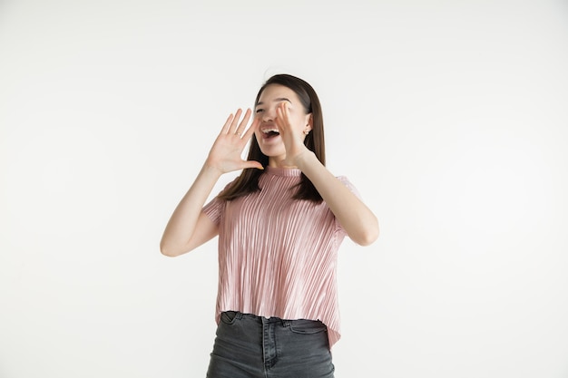 Mooi vrouwelijk half-lengteportret dat op witte studioachtergrond wordt geïsoleerd. Jonge emotionele vrouw in vrijetijdskleding. Menselijke emoties, gezichtsuitdrukking concept. Verbaasd, vroeg zich af, belde om verkoop.