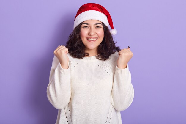 Mooi vrouwelijk model dat de rode Kerstman en witte sweater draagt