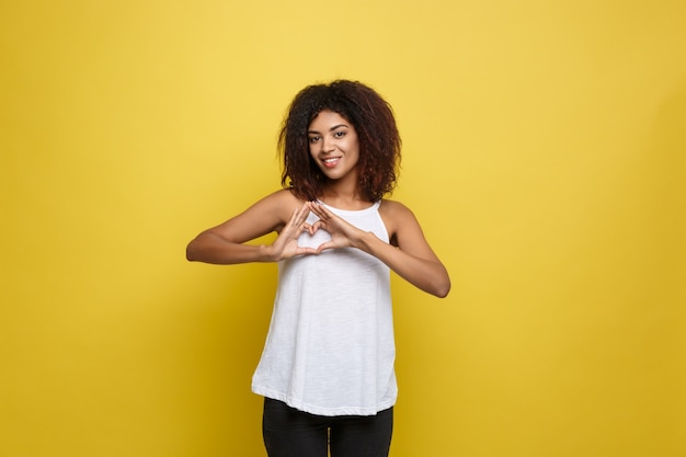 Mooie aantrekkelijke afro-amerikaanse vrouwspelen met haar krullend afro haar. gele studio achtergrond. ruimte kopiëren.