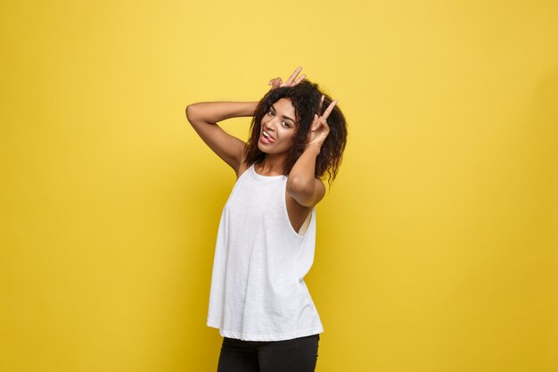 Mooie aantrekkelijke Afro-Amerikaanse vrouwspelen met haar krullend afro haar. Gele studio achtergrond. Ruimte kopiëren.