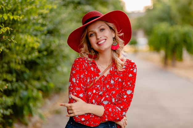 Mooie aantrekkelijke stijlvolle blonde glimlachende vrouw in rode strooien hoed en blouse zomer mode-outfit