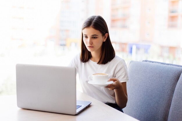 Mooie aantrekkelijke vrouw in het café met een laptop met koffiepauze