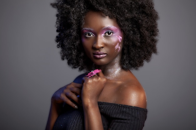 Mooie Afrikaanse vrouw met grote krullende Afro en bloemen in haar haar