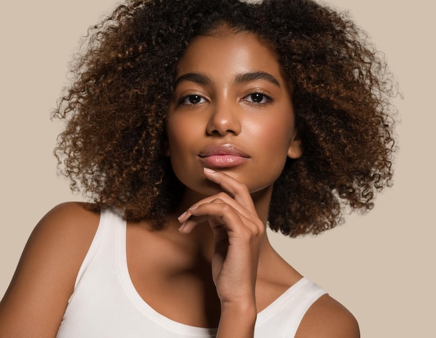 Mooie afrikaanse vrouw wit t-shirt portret afro kapsel wat betreft haar gezicht kleur achtergrond bruin