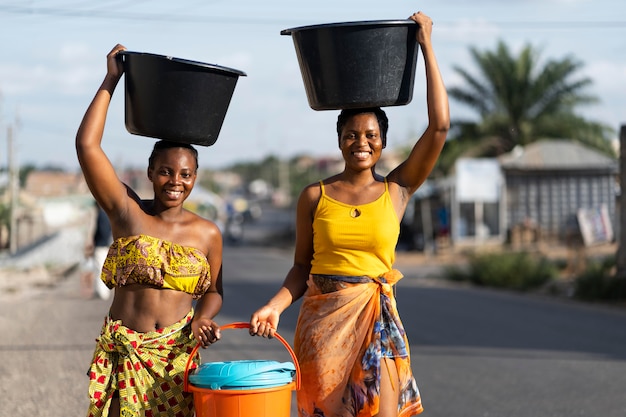 Gratis foto mooie afrikaanse vrouwen die water van buiten halen