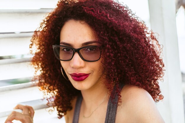 Mooie Afro-Amerikaanse vrouw met krullend rood haar poseren