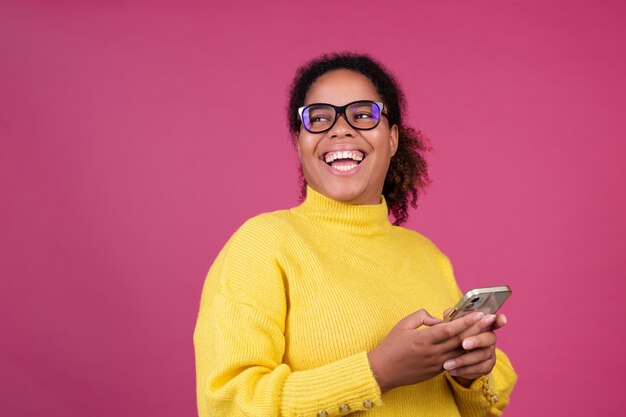 Mooie afro-amerikaanse vrouw op roze muur bericht aan het typen op mobiele telefoon opgewonden blij