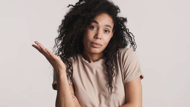 Mooie Afro-vrouw die laat zien dat ik geen uitdrukking op de camera weet op een witte achtergrond