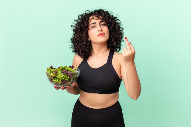Mooie arabische vrouw die zich boos, geïrriteerd, opstandig en agressief voelt en een salade vasthoudt. dieet concept