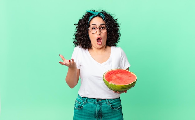 Mooie arabische vrouw die zich extreem geschokt en verrast voelt en een watermeloen vasthoudt. zomer concept