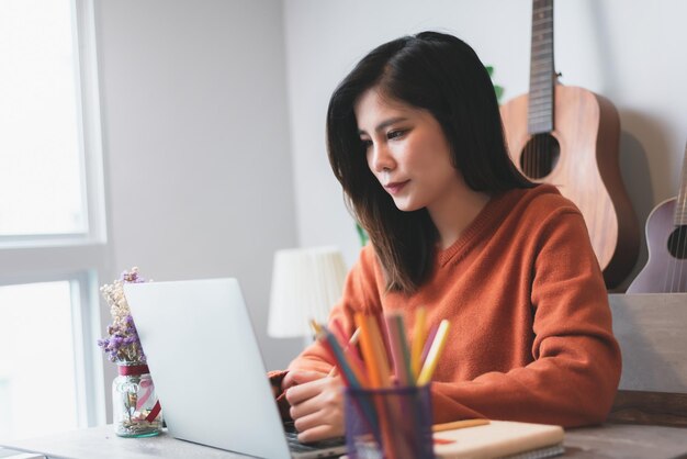 Mooie Aziatische jonge vrouw creatieve freelancer bezig met laptopcomputer werken vanuit huis Concept