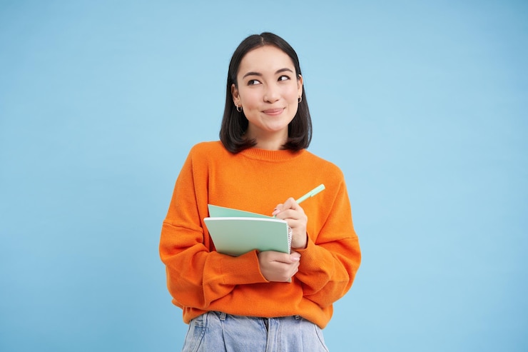 Gratis Foto mooie aziatische studente die aantekeningen maakt terwijl ze studeert op cursussen die over bl staan