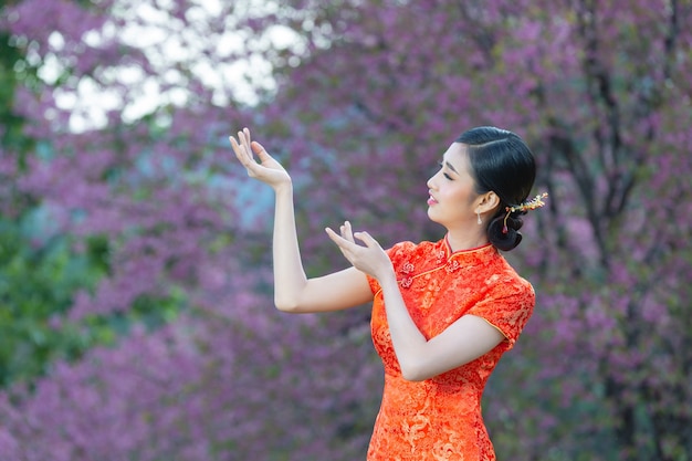 Mooie Aziatische vrouw blije glimlach en laat je iets zien in het chinees nieuwjaar op roze achtergrond.