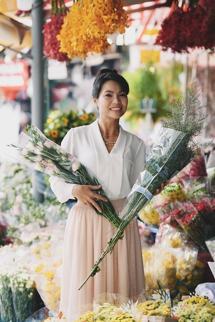 Mooie Aziatische vrouw die boeketten in bloemwinkel kiezen