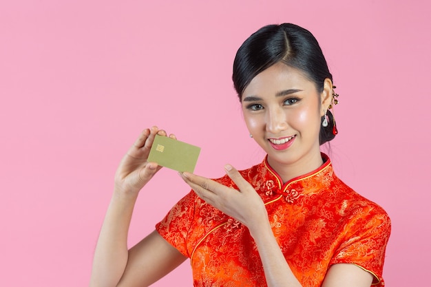 Mooie aziatische vrouw gelukkige glimlach en toon creditcard in chinees nieuwjaar op roze achtergrond.