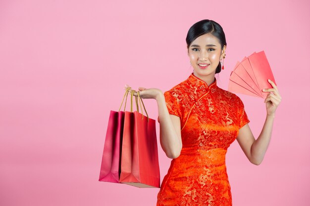 Mooie Aziatische vrouw gelukkige glimlach en winkelen in Chinees Nieuwjaar op roze achtergrond.