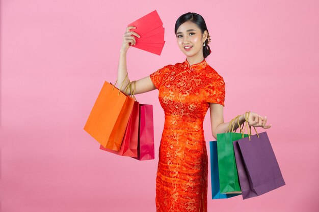 Mooie aziatische vrouw gelukkige glimlach en winkelen in chinees nieuwjaar op roze achtergrond.