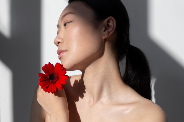 Mooie Aziatische vrouw poseren met roos met perfecte huid
