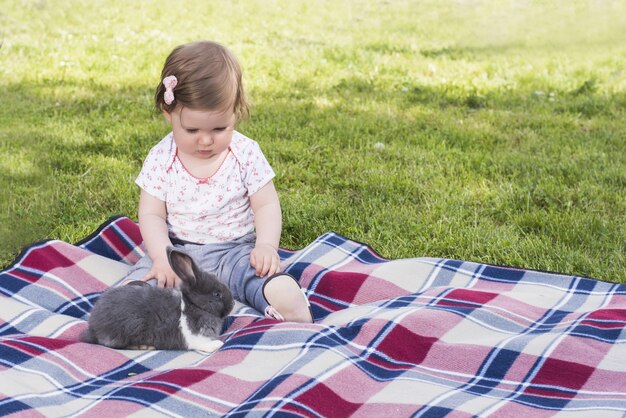 Mooie baby spelen met konijntje op deken