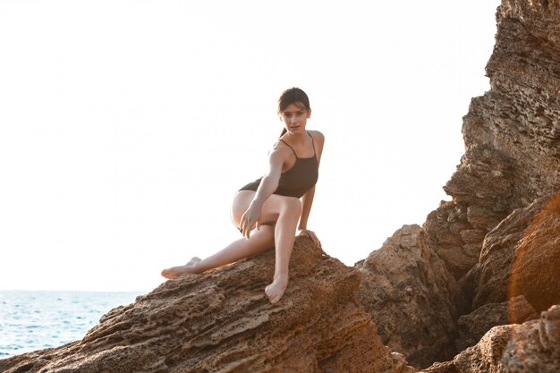 Mooie ballerina dansen, die zich voordeed op rots op het strand, uitzicht op zee.