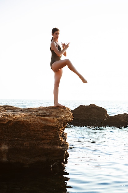 Mooie ballerina dansen, die zich voordeed op rots op het strand