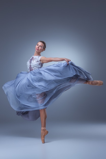 mooie ballerina dansen in lange blauwe jurk op blauwe achtergrond