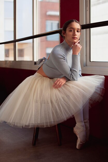 Mooie ballerina in tutu rok poseren naast raam