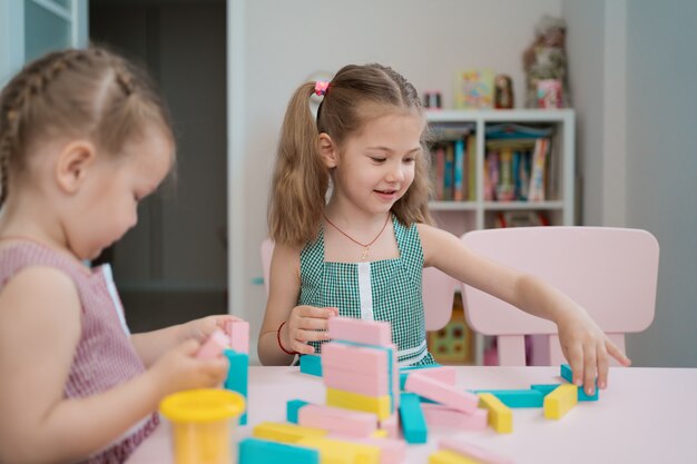 Mooie blanke meisjes spelen met houten veelkleurige blokken