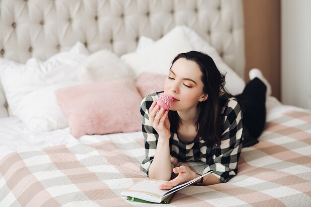 Mooie blanke vrouw met kort donker haar in een gezellige trui houdt een boek vast na een moeilijke dag