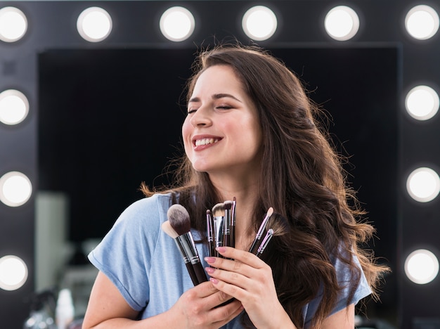 Gratis foto mooie blije vrouw make-up stylist met borstels in handen