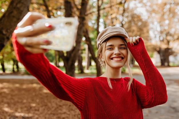 Mooie blonde met mooie glimlach poseren voor selfie in park.