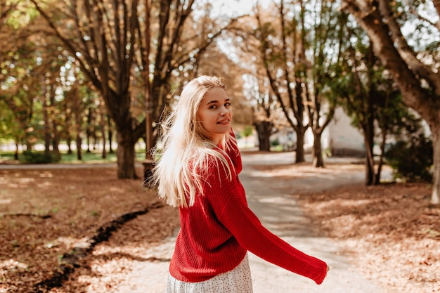 Mooie blonde op zoek gelukkig in herfst park. Mooi meisje voelt zich ontspannen met mooi weer aan de muur.