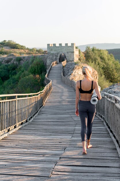 Mooie blonde vrouw met yogamat