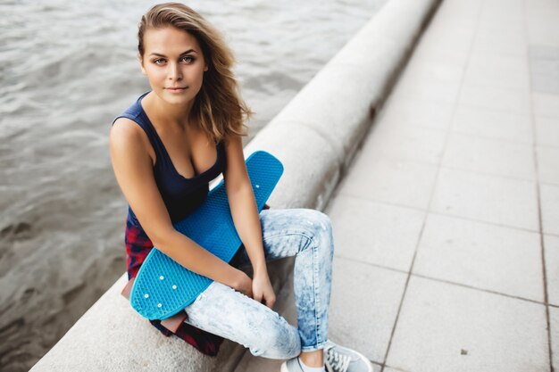 mooie blonde vrouw poseren met een skateboard