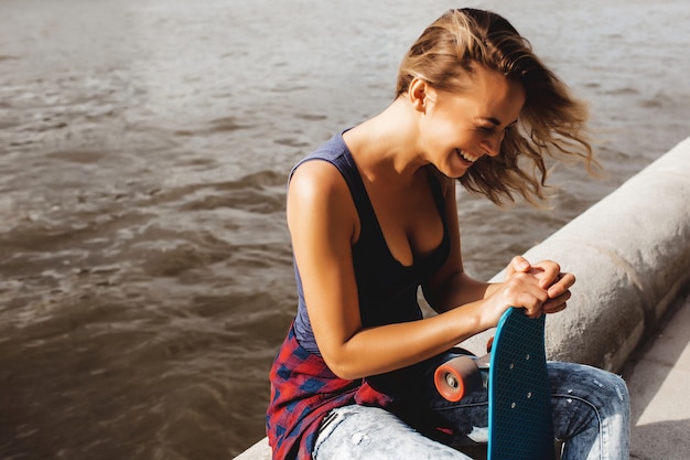 mooie blonde vrouw poseren met een skateboard