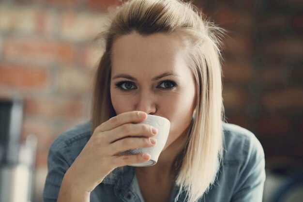 Mooie blonde vrouw poseren met koffiekopje