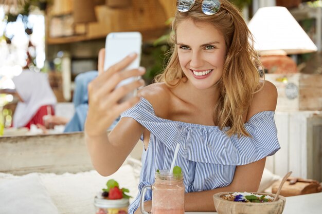 Mooie blonde vrouw zitten in café