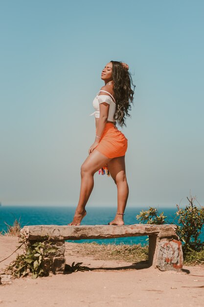 Mooie Braziliaanse model poseren op een bankje aan het strand