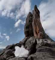 Gratis foto mooie bruid staat op de rots in de buurt van de hoge klif op de heldere dag met blauwe hemel