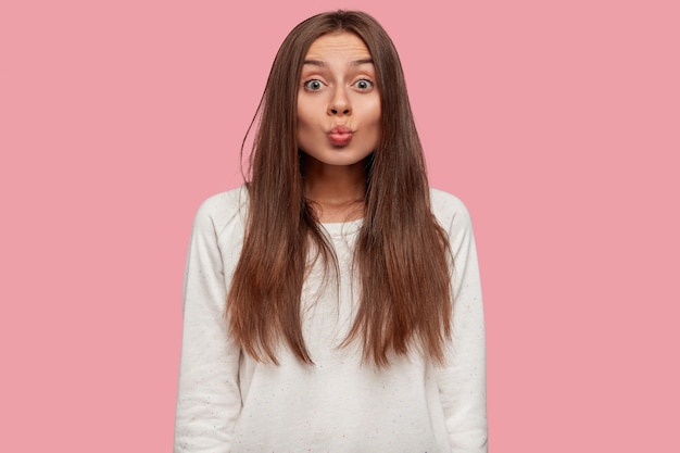 mooie brunette poseren tegen de roze muur