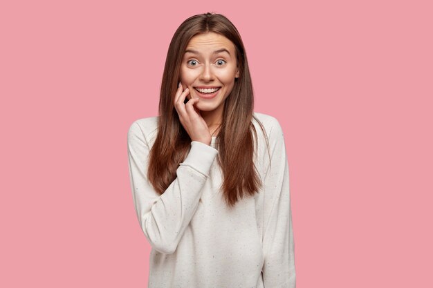 mooie brunette poseren tegen de roze muur