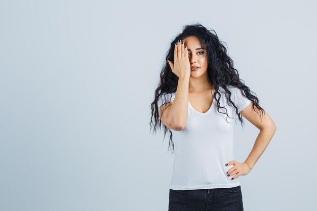 Mooie brunette vrouw in een wit t-shirt dat een oog bedekt