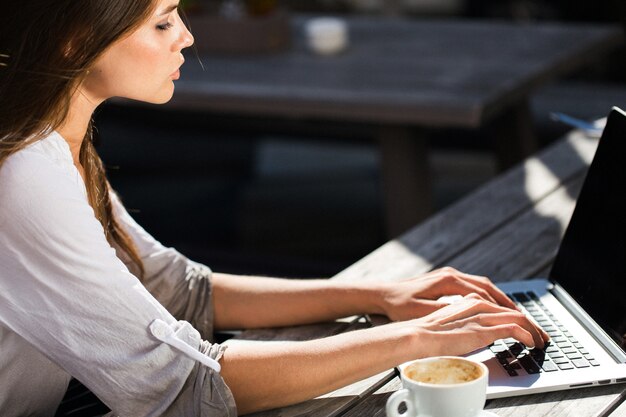 Mooie brunette werkt met laptop buiten