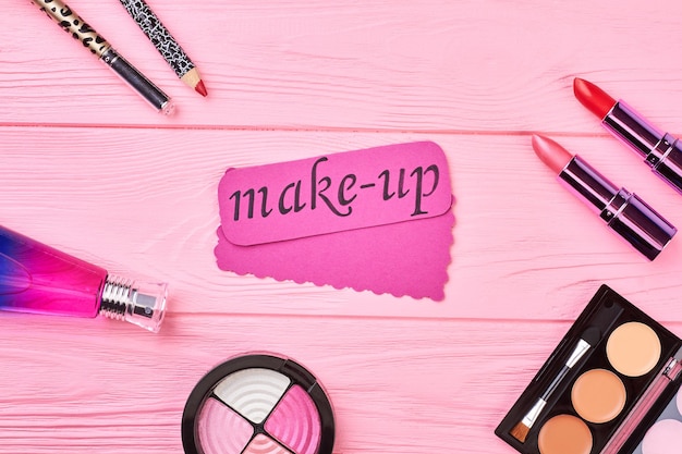 Mooie cosmetica set voor fashion make-up. vrouwelijk oogschaduwpalet, parfum en lippenstift. roze make-up kaart op kleur achtergrond. vrouw schoonheid accessoires.