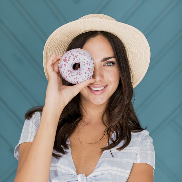 Mooie dame die haar oog bedekt met een donut