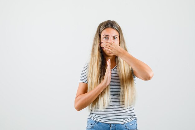 Mooie dame die neus knijpt als gevolg van slechte geur in t-shirt en walgt. vooraanzicht.