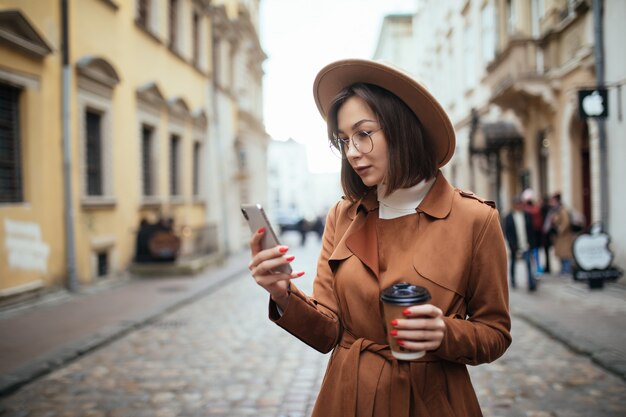 Mooie dame die op mobiele telefoon spreekt die in openlucht in koude de herfstdag loopt