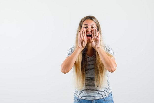 Mooie dame die voor iemand in t-shirt schreeuwt en gefocust, vooraanzicht kijkt.