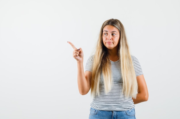 Mooie dame die weg in t-shirt wijst en aandachtig kijkt. vooraanzicht.