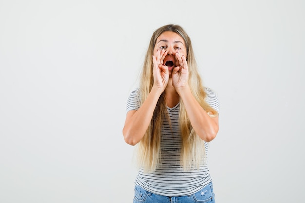 Mooie dame in t-shirt die om hulp schreeuwt en ongeduldig kijkt, vooraanzicht.